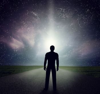 Man standing alone on the road looking at the night sky, universe, falling stars. Dream, adventure, future, explore concepts. Man standing on the road looking at stars, sky, universe. Dream, adventure.