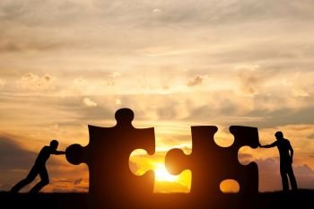 Two men connect two puzzle pieces. Sunset sky. Concept of business solution, teamwork, solving a problem, challenge. Two men connect two puzzle pieces. Concept of business solution, solving a problem.