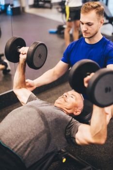 Personal trainer assisting older man in an exercise. Retirement activities. Health.. Personal trainer assisting older man in an exercise