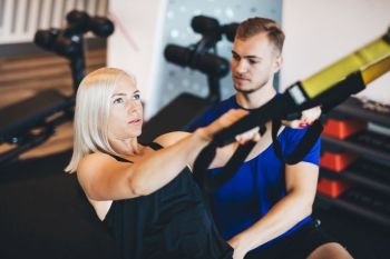 Young woman exercising with personal trainer at the gym. Healthy lifestyle and fitness.. Young woman exercising with personal trainer.