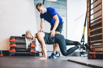 Woman exercising with personal trainer at the gym. Sportive lifestyle. Body shaping.. Woman exercising with personal trainer at the gym.