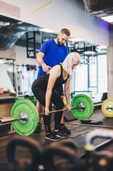 Personal trainer assisting woman lifting weights. Fitness club. Sporty lifestyle.. Personal trainer assisting woman lifting weights.