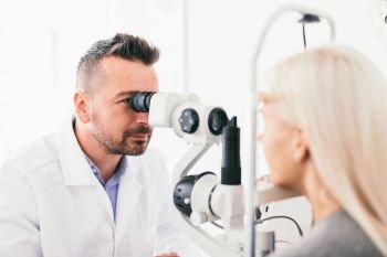 Optician examining his patients eyesight. Healthcare, professional medical equipment.. Optician examining his patients eyesight.
