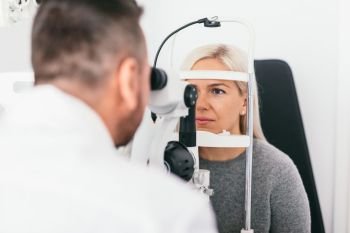 Woman undergoing eyesight exam in optician’s office. Ophthalmology, vision examination and treatment.. Woman undergoing eyesight exam in optician’s office.