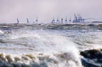 Stormy sea and industrial landscape in the background. Gdynia, Poland, Baltic Sea.. Stormy sea and industrial landscape