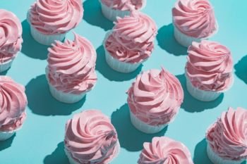 Pink cupcakes on a pastel blue background. Minimalism. Delicious sweet cakes.. Pink cupcakes on a pastel blue background.