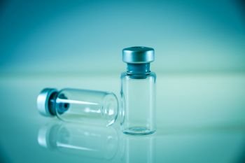 two vaccine glass bottles on blue background. two vaccine bottles on blue background