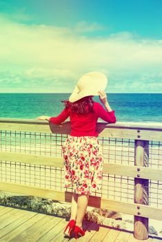 beautiful woman in red standing and looking to the sea  in retro style