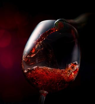 Wine pouring in wineglass on a vinous background