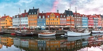 Nyhavn at sunrise, with colorful facades of old houses and old ships in the Old Town of Copenhagen, capital of Denmark.. Nyhavn at sunrise in Copenhagen, Denmark.
