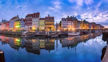 Panoramic view of Nyhavn with colorful facades of old houses and old ships in the Old Town of Copenhagen, capital of Denmark.. Nyhavn in Copenhagen, Denmark.