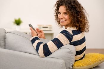 Beautiful woman sitting on the sofa and sending a text message