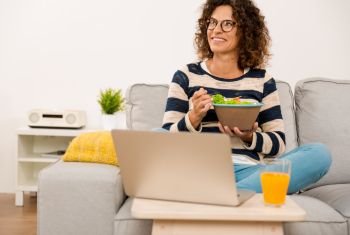 Beautiful woman at home making a pause of work to eat a salad