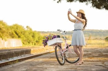 A beautiful young woman with her bicycle and making a selfie