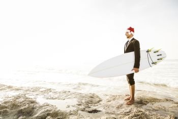 Business surfist wearing a Santa hat and holding a surfboard