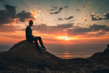 Young man sitting and watching a beautiful sunset