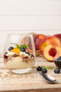 Granola with peaches, yogurt and blueberries on wooden table