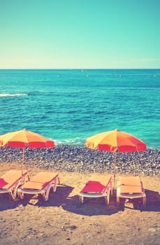 Umbrellas and chaise longues on a sea beach, Tenerife. Retro style filtered image