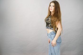 Feminine beauty concept. Portrait of beautiful young woman with long brown hair wearing stylish camo pattern tshirt and jeans. Beautiful young woman with brown hair