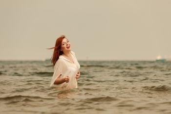 Summer fun, recreation outside concept. Redhead adult woman playing in water during summertime, having great time and smiling joyfully. Redhead woman playing in water during summertime