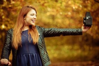 Beauty makeup nature forest autumn concept. Ginger girl taking selfie. Young attractive redhead lady takes picture of herself.. Ginger girl taking selfie.