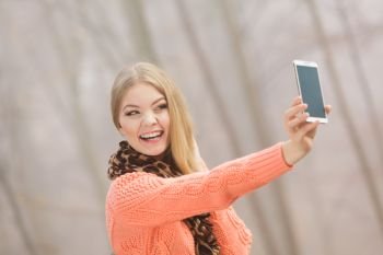 Happy fashion woman in fall autumn park taking selfie self photo picture. Pretty joyful young girl in sweater pullover photographing.. Happy fashion woman in park taking selfie photo.