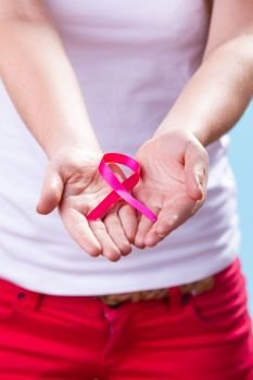Healthcare and medicine concept - woman showing pink breast cancer awareness ribbon on hands, closeup. Woman with breast cancer awareness ribbon on hands