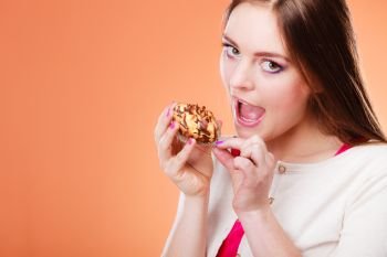 Bakery, sweet food and people concept. Woman wide open mouth holds cake cupcake in hand orange background
