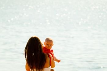 Summer family recreation concept. Mother holding and playing with little baby on beach during summertime.. Mother playing with baby on beach