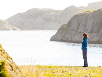 Tourism vacation and travel. Woman tourist enjoying ocean view from rocky coast, Norway Scandinavia.. Woman tourist looking at ocean in Norway