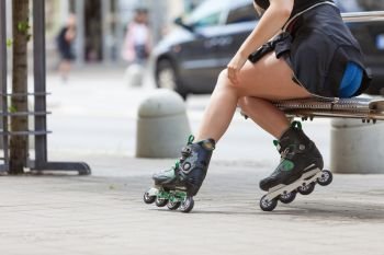 Woman wearing roller skates sitting in town. Female being sporty during summer time.. Woman wearing roller skates