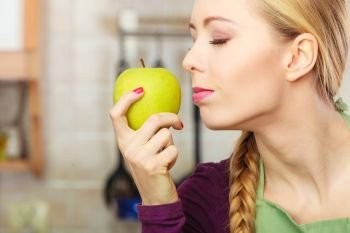Woman young female long haired holding big green yellow apple fruit. Healthy eating, vegetarian food, dieting and people concept.. Woman young housewife in kitchen with apple fruit