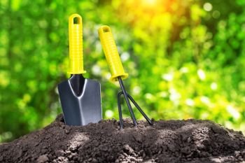 Garden tools in a pile of earth against the background of green foliage. Garden tools in pile of earth against background of green foliage