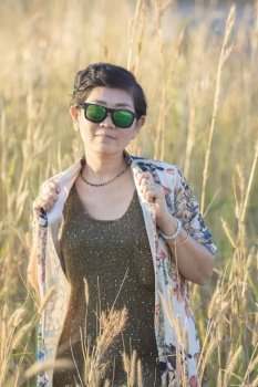 beautiful asian woman wearing sunglasses standing in grass field 