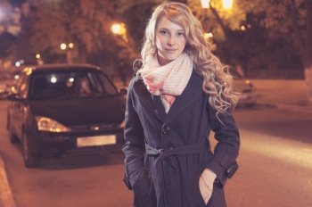 Young blond woman walking on the street, car on background