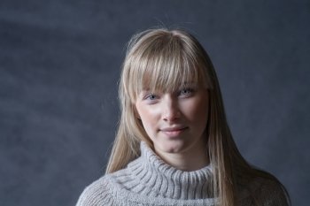 Headshot of blond haired women. Elegant young woman in a jumper  on a dark background