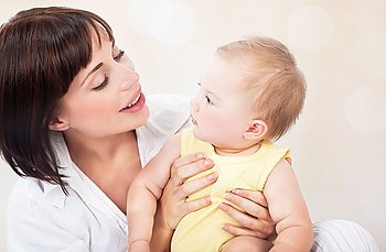 Portrait of happy young mother with cute little daughter on blur background, beautiful woman enjoying parenthood, family love concept