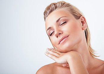 Portrait of gentle calm girl with closed eyes and hand near face over light background, natural skin care, perfect complexion, enjoying day spa