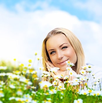 Beautiful woman enjoying daisy field and blue sky, nice female lying down in the meadow of flowers, pretty girl relaxing outdoor, happy young lady and green spring nature in harmony