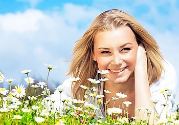 Young beautiful girl laying on the daisy flowers field, outdoor portrait, summer fun concept