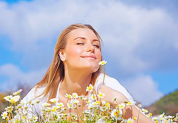 Happy young female lying on the flower field, over blue cloudy sky, with copyspace, leisure, fun and wellness concept