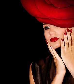 Photo of gorgeous luxury model with festive makeup wearing glamorous floral hat with great red rose isolated on black background, fashionable accessories, sexy female, passion and seduction concept