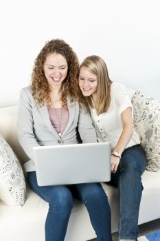 Two women using laptop computer. Two young smiling women using laptop computer at home