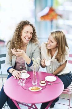 Two women having coffee. Two smiling women meeting for coffee in cafe and laughing