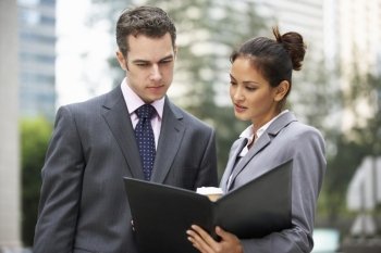 Businessman And Businesswoman Discussing Document Outside Office