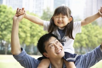 Chinese Father Giving Daughter Ride On Shoulders In Park