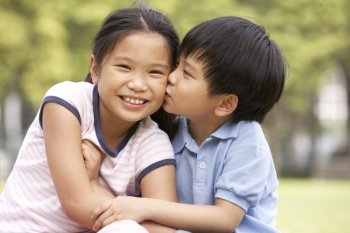Portrait Of Chinese Boy And Girl Sitting In Park Together