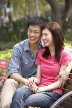 Young Chinese Couple Relaxing On Park Bench Together