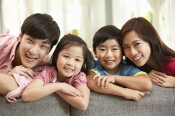 Chinese Family Sitting And Relaxing On Sofa Together At Home