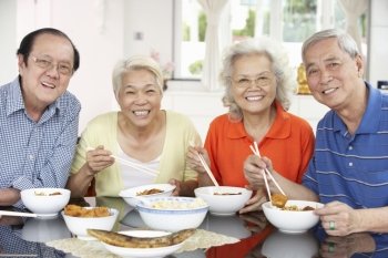 Group Of Senior Chinese Friends Eating Meal At Home